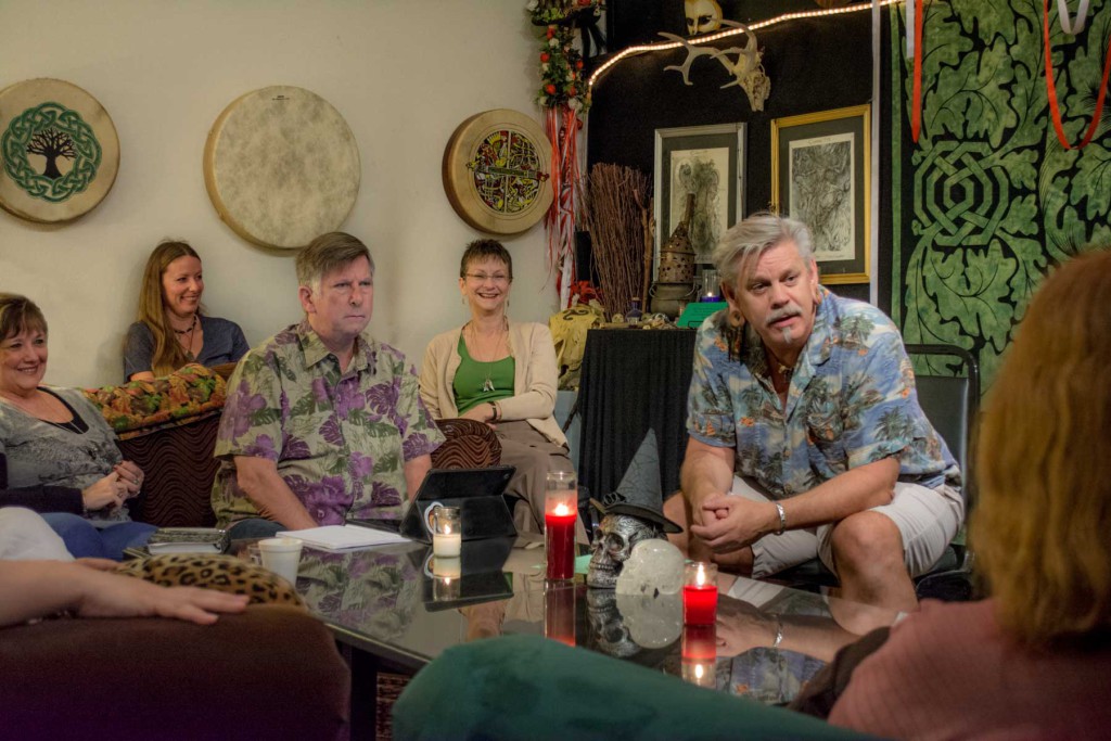 Students gathered around a table listening to a lecture in our classroom