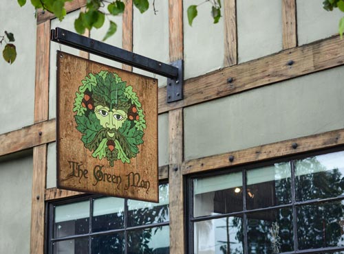 Photo that shows a sign with the Green Man logo and "The Green Man" below it, which hangs outside our shop on Lankershim Ave in North Hollywood